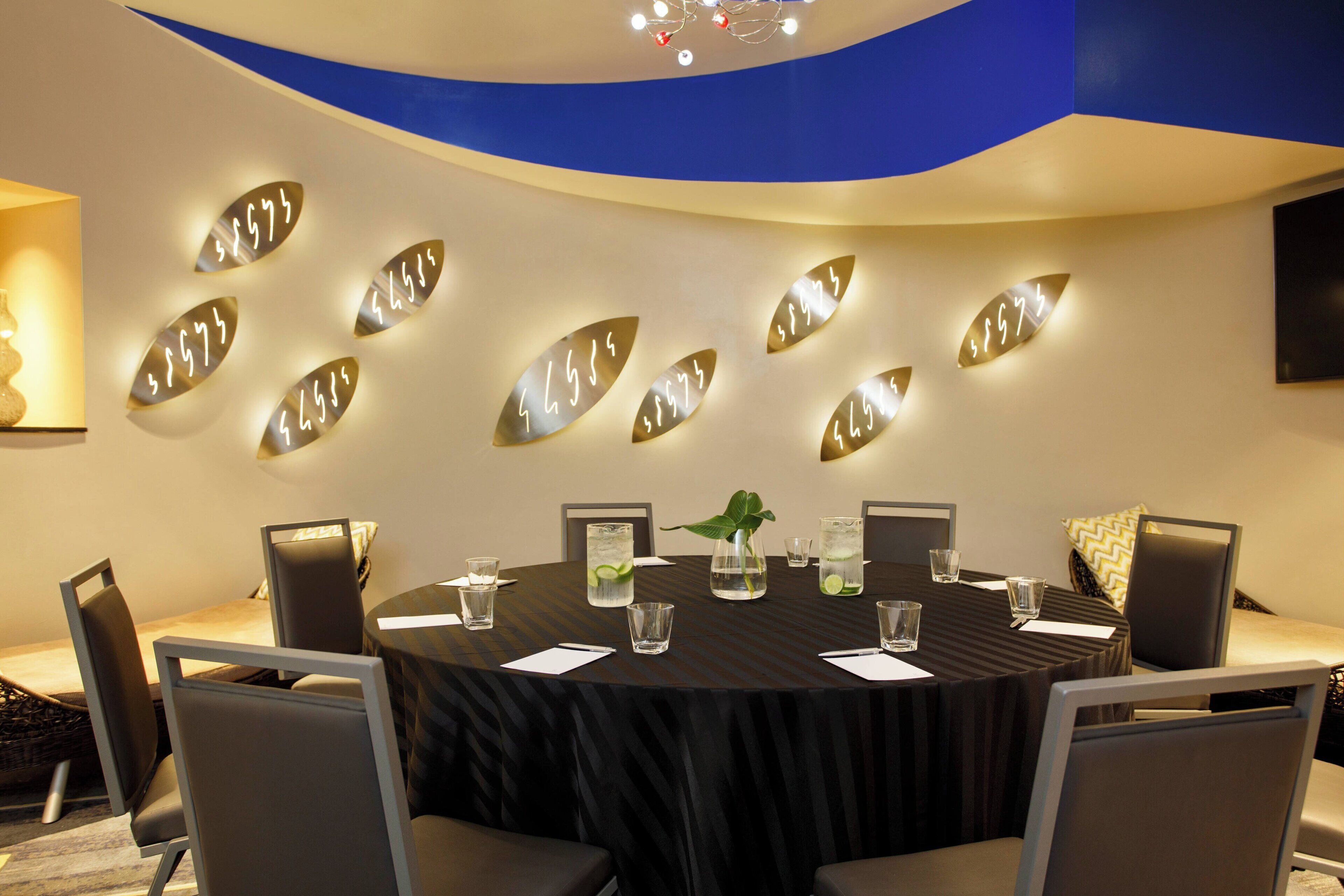 A conference room with a round table, chairs, and a decorative wall with illuminated numbers.