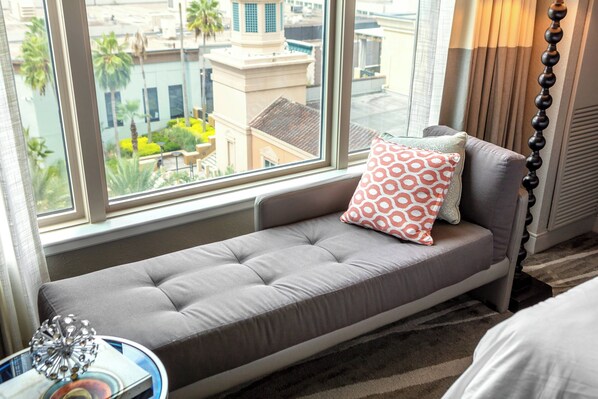 Asiento junto a la ventana con un banco acolchado, un cojín estampado y una lámpara a su lado.