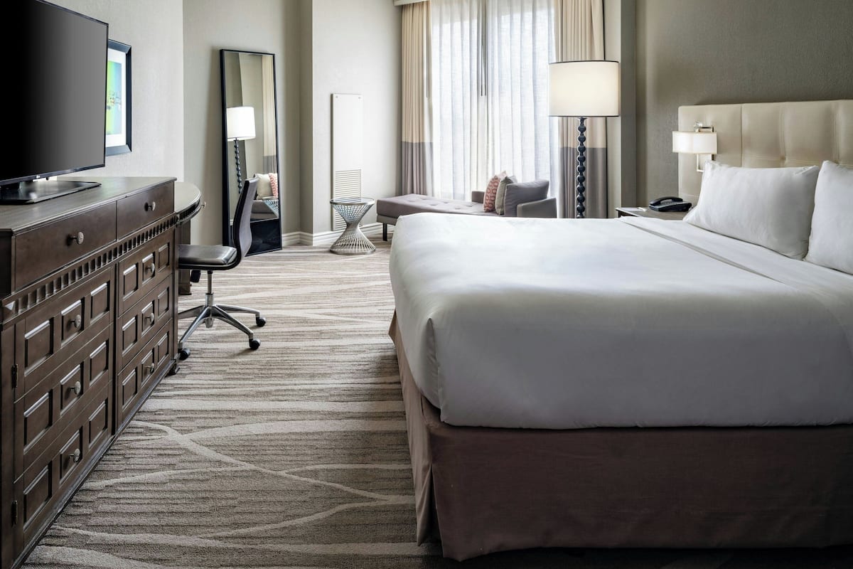 Een hotelkamer met een groot bed, een televisie, een bureau en een stoel.