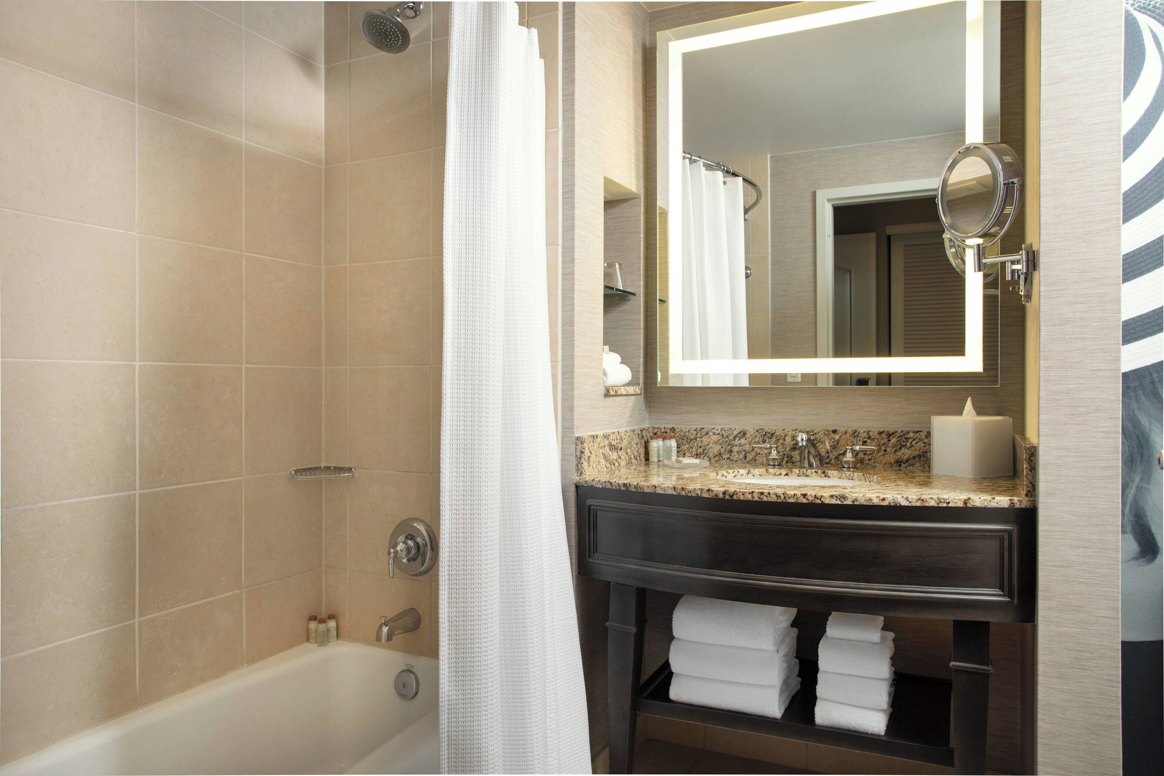 A bathroom with a bathtub, a vanity with a mirror, and a towel rack.