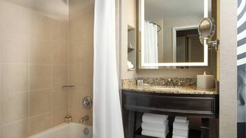 A bathroom with a bathtub, a vanity with a mirror, and a towel rack.