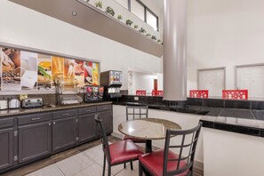 Una cucina moderna con piani in granito, un tavolo da pranzo rotondo e sedie rosse.