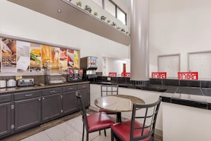 Una cocina moderna con encimeras de granito, una mesa de comedor redonda y sillas rojas.
