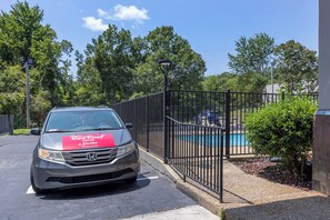 A Honda van parked in front of a gated area with a swimming pool visible in the background.