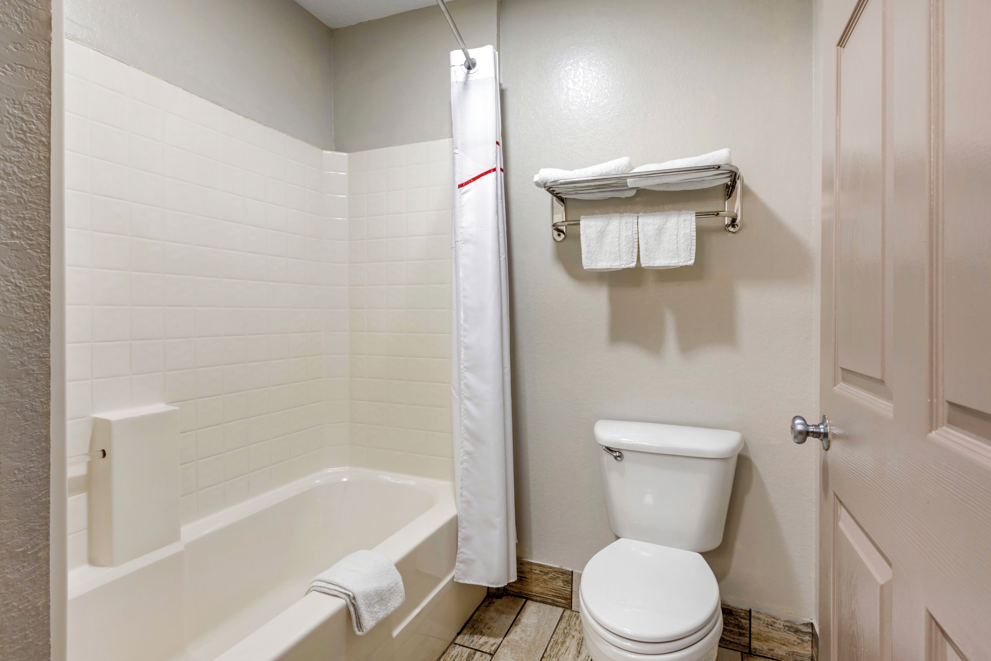 A bathroom with a bathtub, toilet, and a shower curtain.