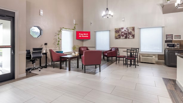 A modern office space with a conference table, red chairs, a whiteboard, and a sign indicating free Wi-Fi availability.