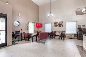 Un espacio de oficina moderno con una mesa de conferencias, sillas rojas, una pizarra y un letrero que indica acceso a internet Wi-Fi gratuito.