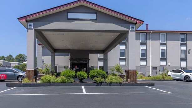 A modern building with a covered entrance, a parking lot, and a clear sky. - Red Roof Inn & Suites Clinton, MS (Clinton)
