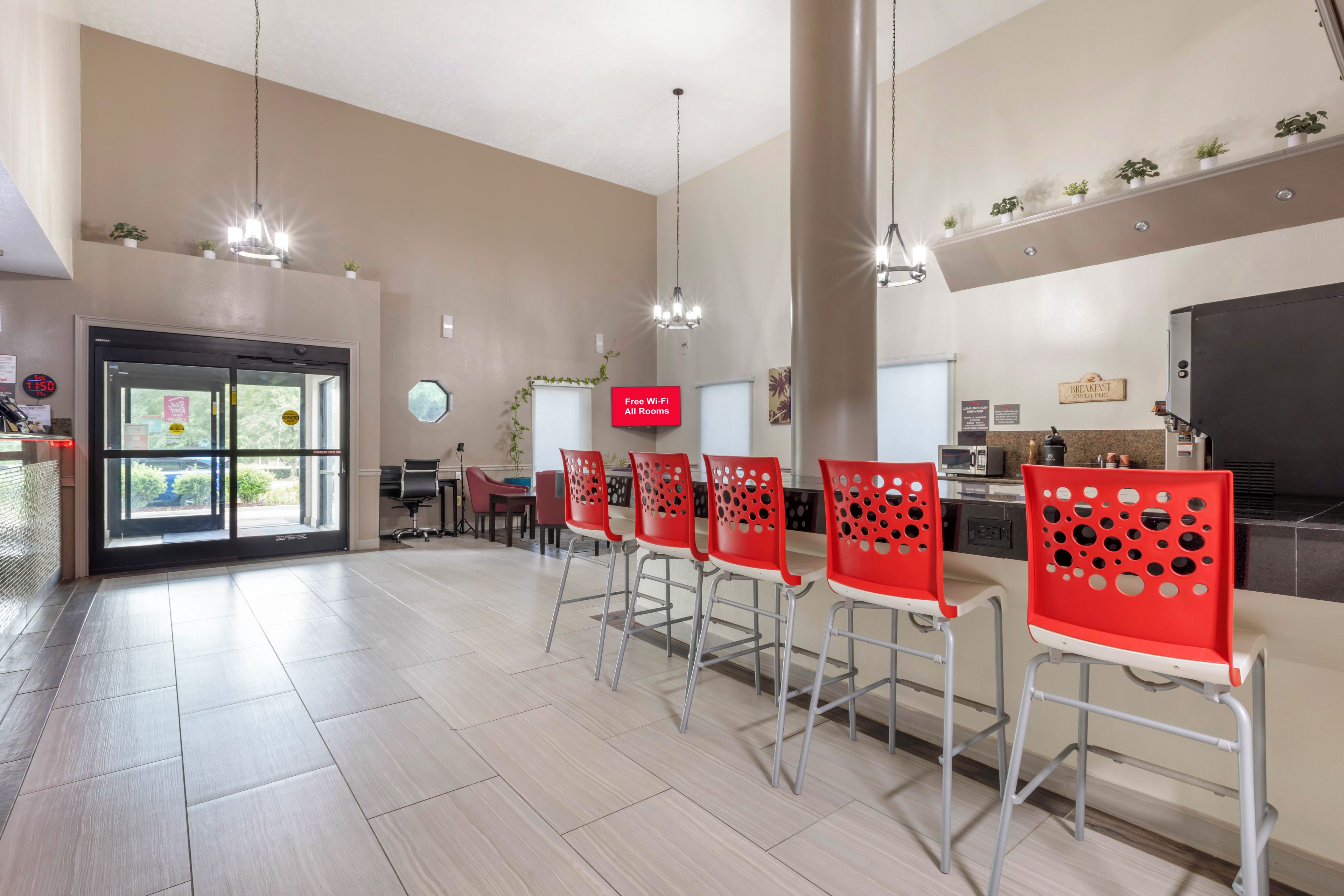 Amplia cocina con electrodomésticos modernos, barra de desayuno con sillas rojas y un cartel que indica acceso a Wi-Fi gratuito.