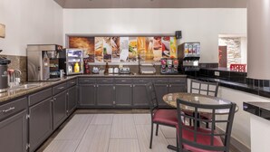 A modern kitchen with granite countertops, stainless steel appliances, and a dining area with a round table and chairs.
