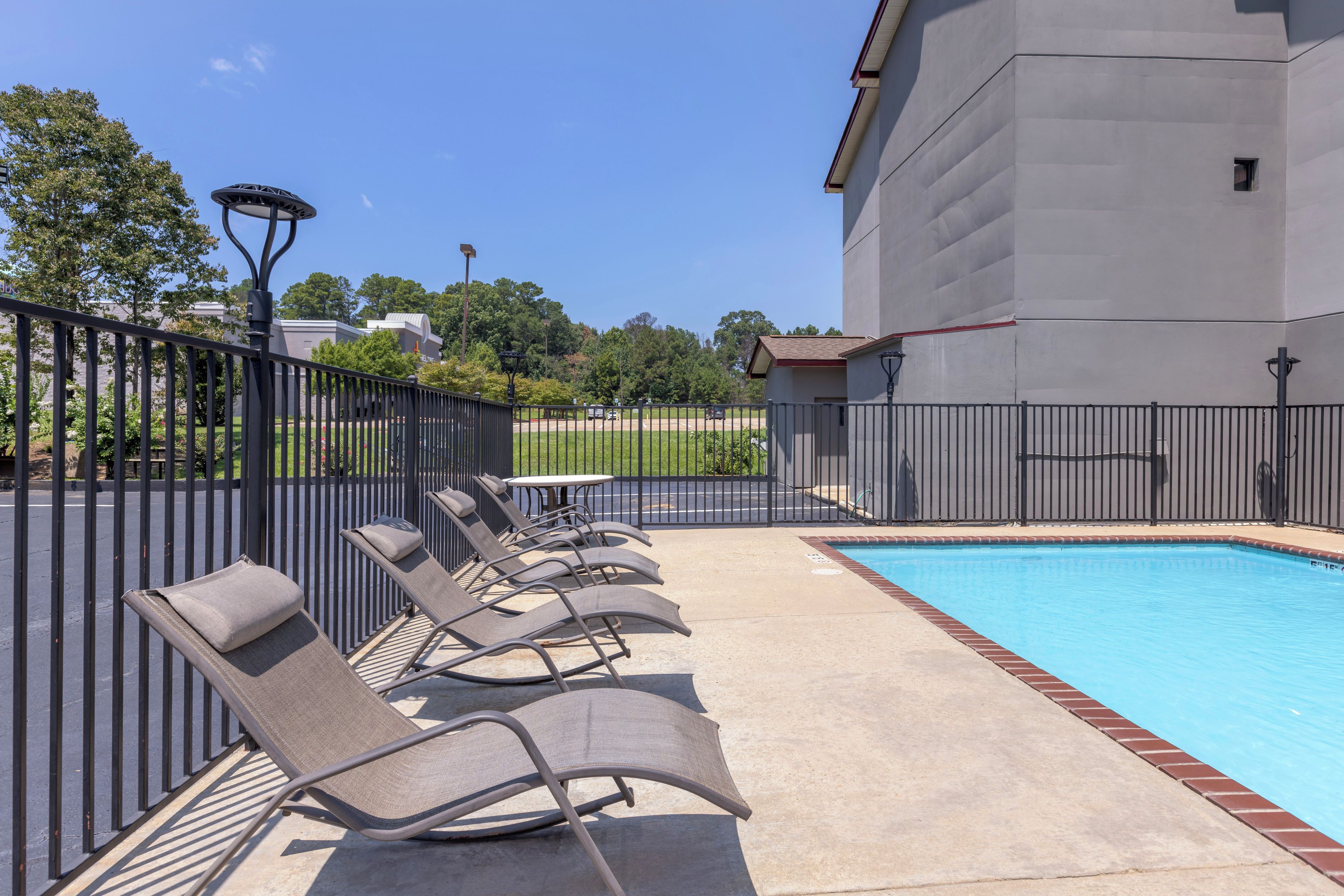 A swimming pool with lounge chairs and a fence.
