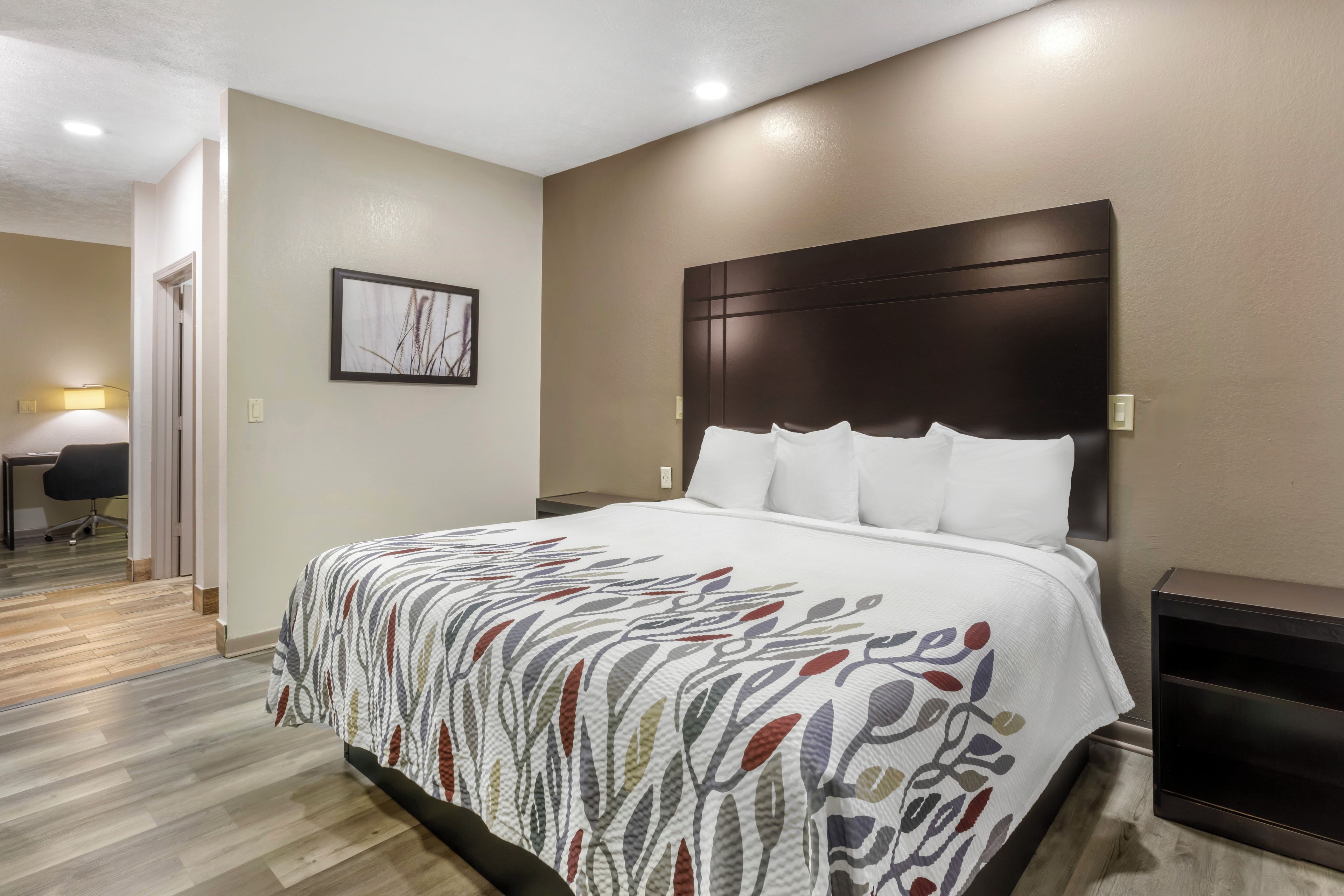Una habitación de hotel con una cama grande, cabecero, escritorio y una silla.