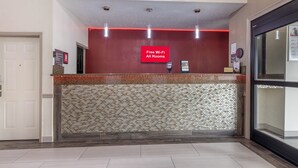 A reception area with a red wall, a mosaic tile wall, and a sign stating "Free Wi-Fi All Rooms."