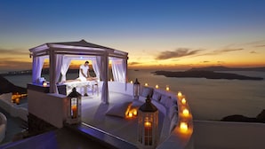 A serene spa setting with a massage table under a canopy, overlooking a scenic ocean view at sunset. - Volcano View Hotel Santorini (Santorini)