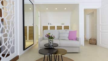 Una sala moderna con un sofá, dos mesas redondas y un espejo decorativo.