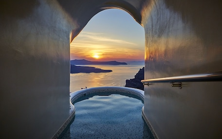A view from a bathtub to a sunset over water, with a clear sky and distant land.