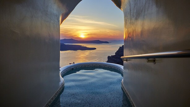 A view from a bathtub to a sunset over water, with a clear sky and distant land. - Volcano View Hotel Santorini (Santorini)