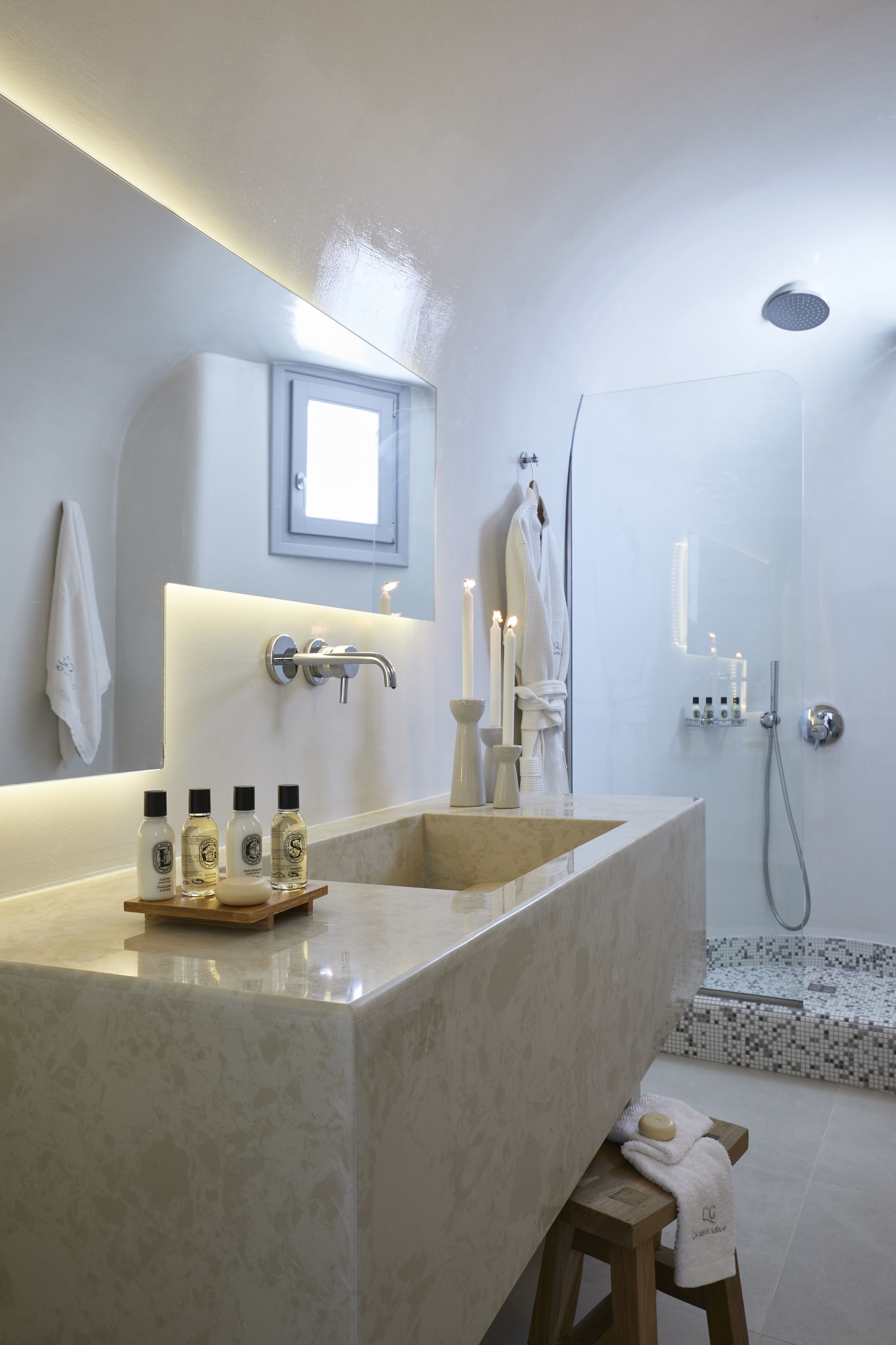 Une salle de bain moderne avec un grand lavabo en marbre, une douchette à main et une douche à l’italienne.