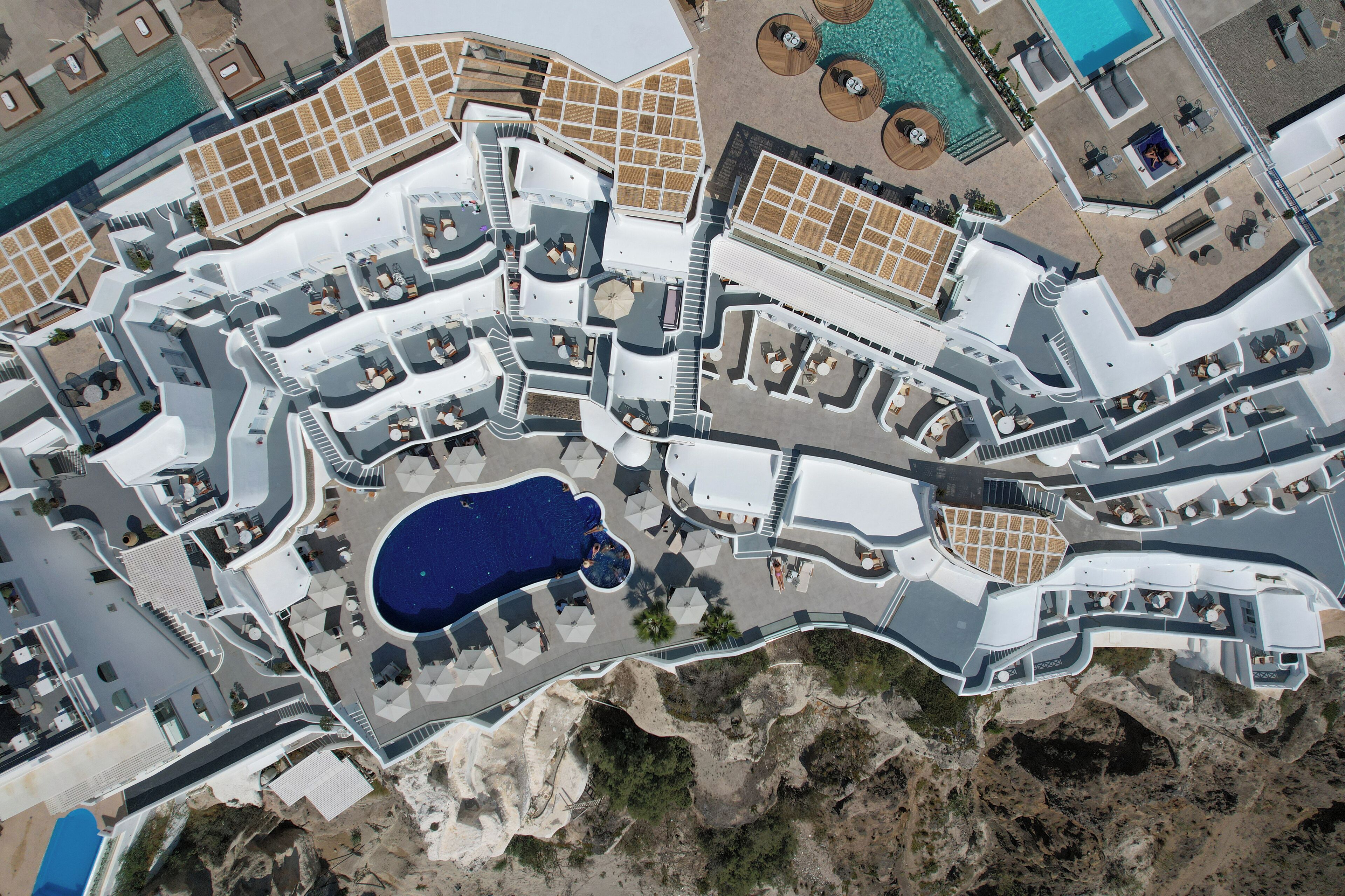 Vista aérea de un complejo turístico con varias piscinas, zonas de estar al aire libre y un patio central.