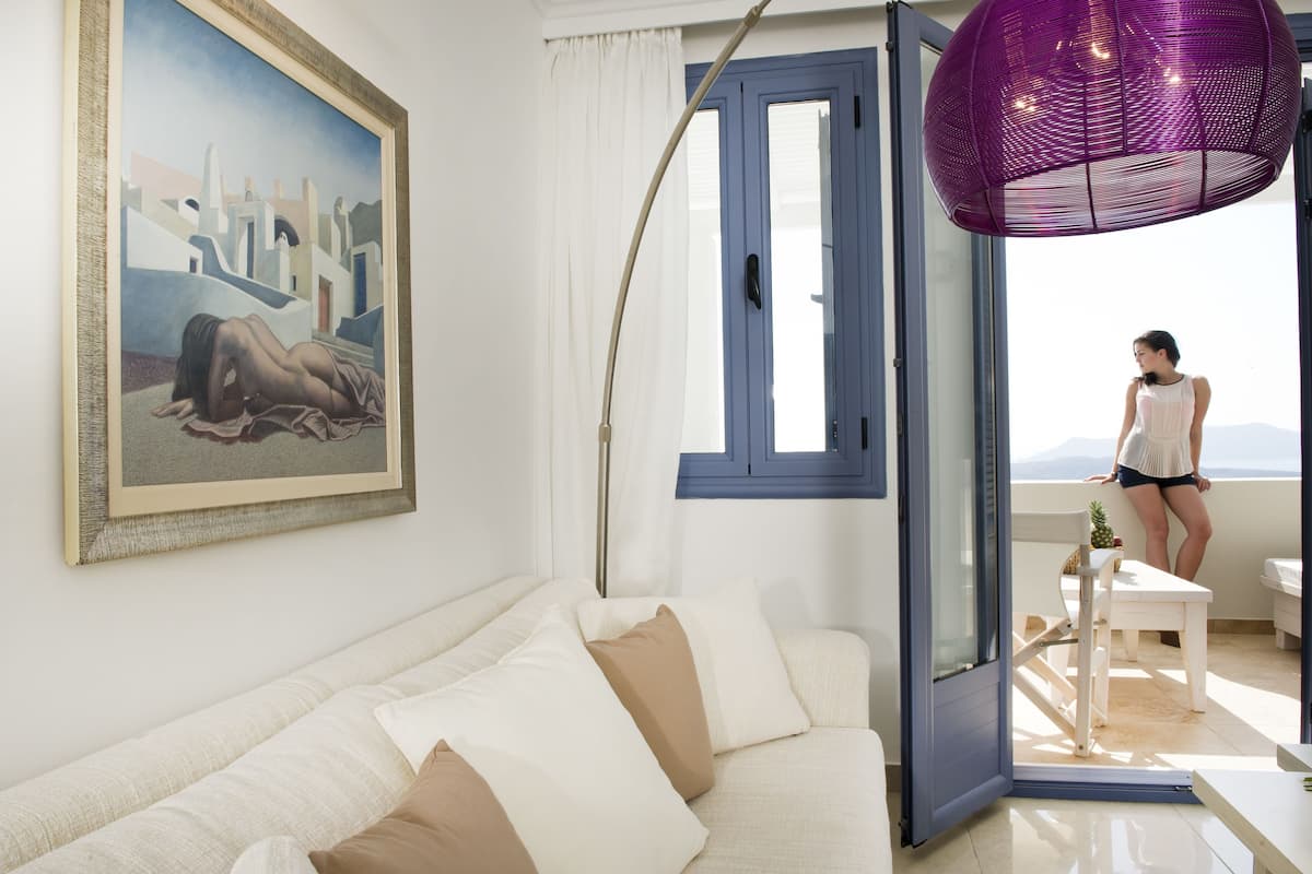 A modern living room with a sofa, a painting, a large window, and a balcony.