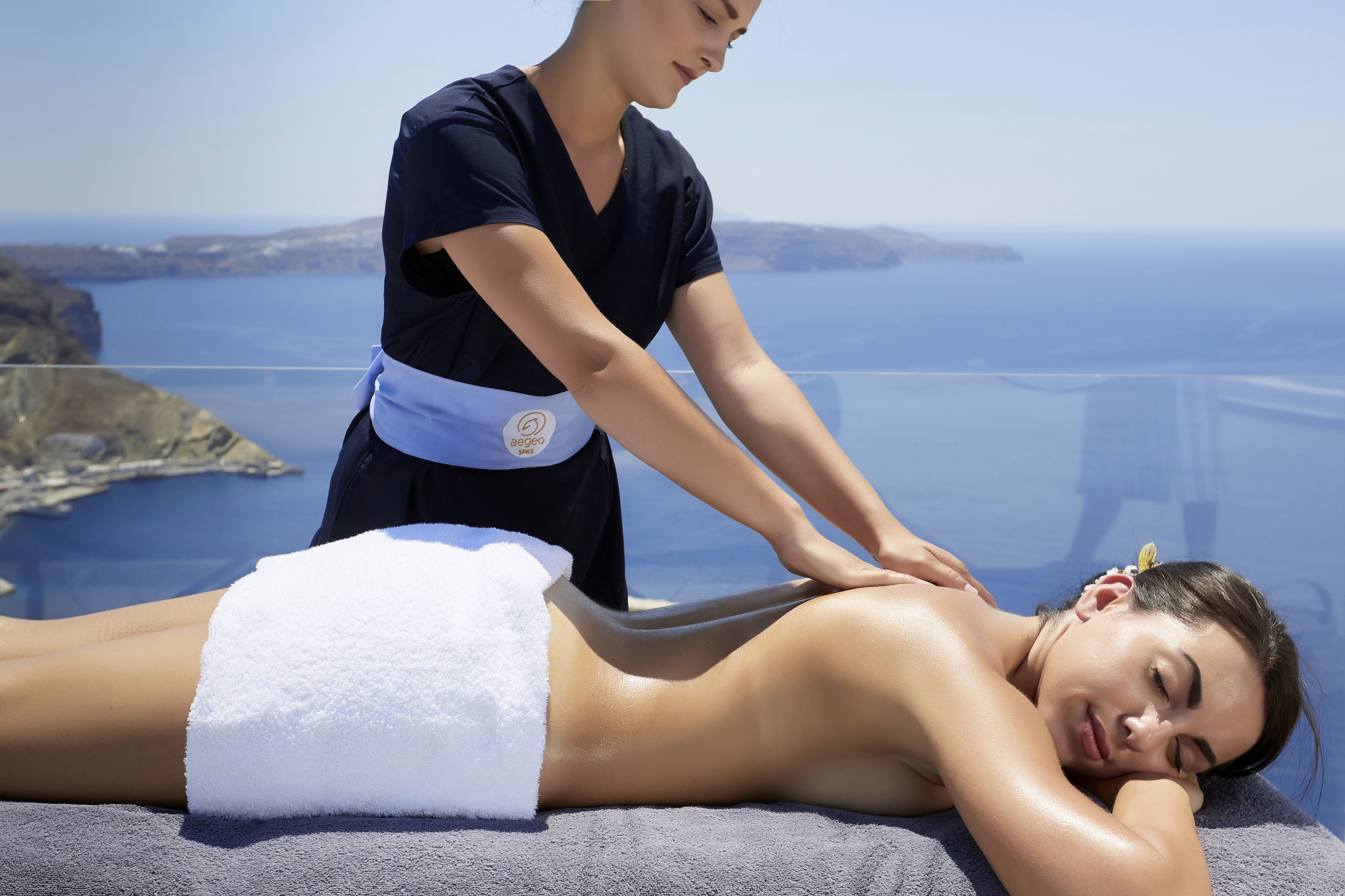 A massage therapy session on a cliff overlooking the sea, with a clear view of the coastline.