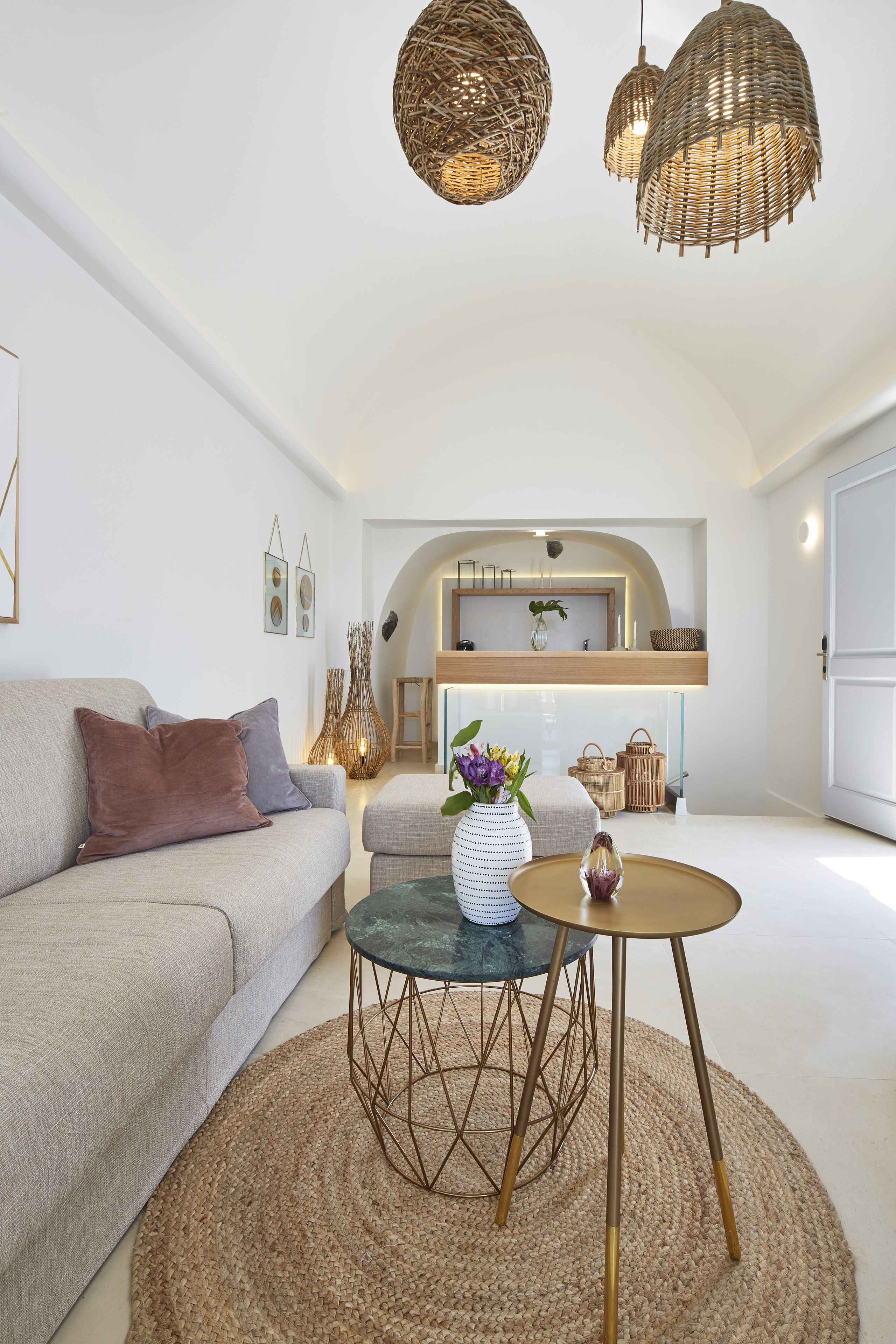 A modern living room with a sofa, round coffee table, and wicker pendant lights.