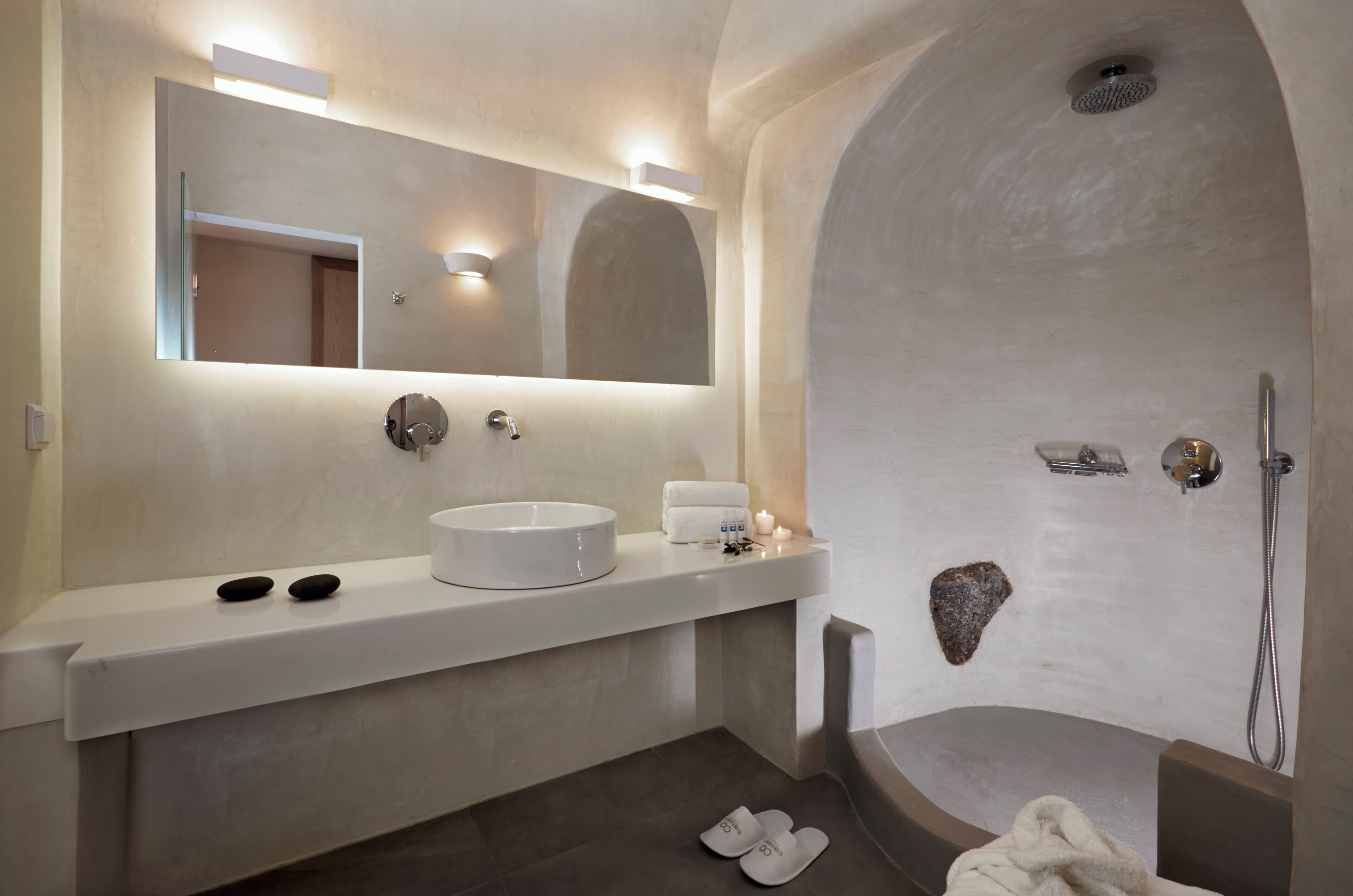 Een moderne badkamer met een grote spiegel, een rond wastafelmeubel, een douche en een bad.