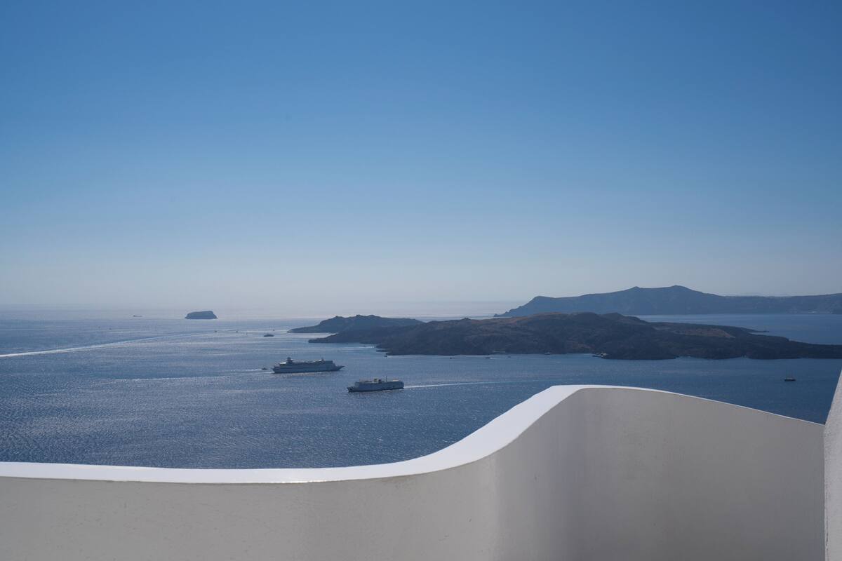 A view of a coastal area with a clear sky, calm sea, and a few boats.