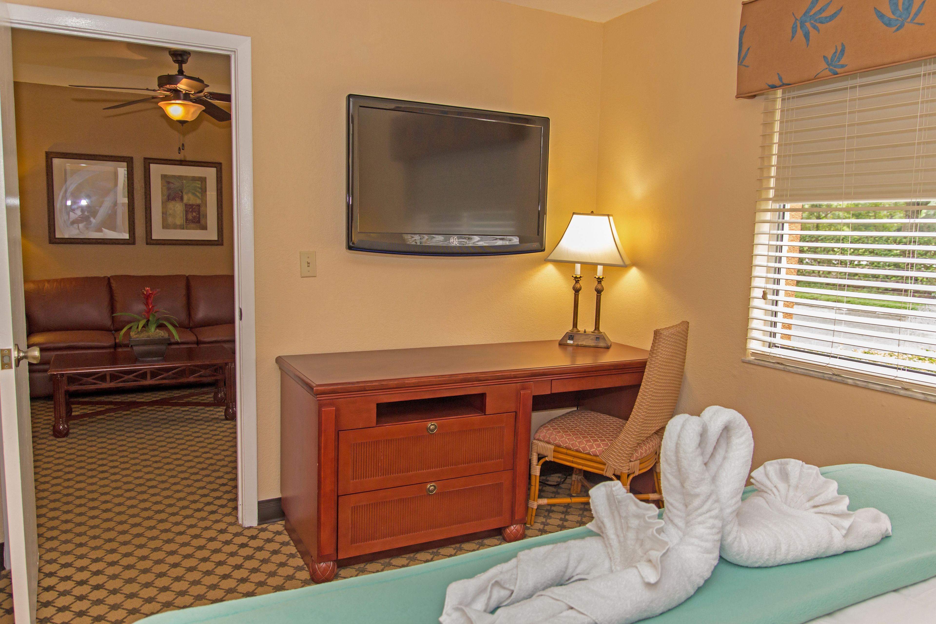 Ein Hotelzimmer mit Bett, Schreibtisch, Stuhl, Fernseher und einem Fenster mit Jalousien.