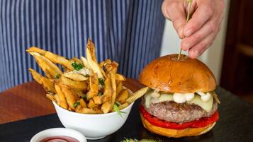 Een maaltijd bestaande uit een hamburger en frietjes, met ketchup en augurken.