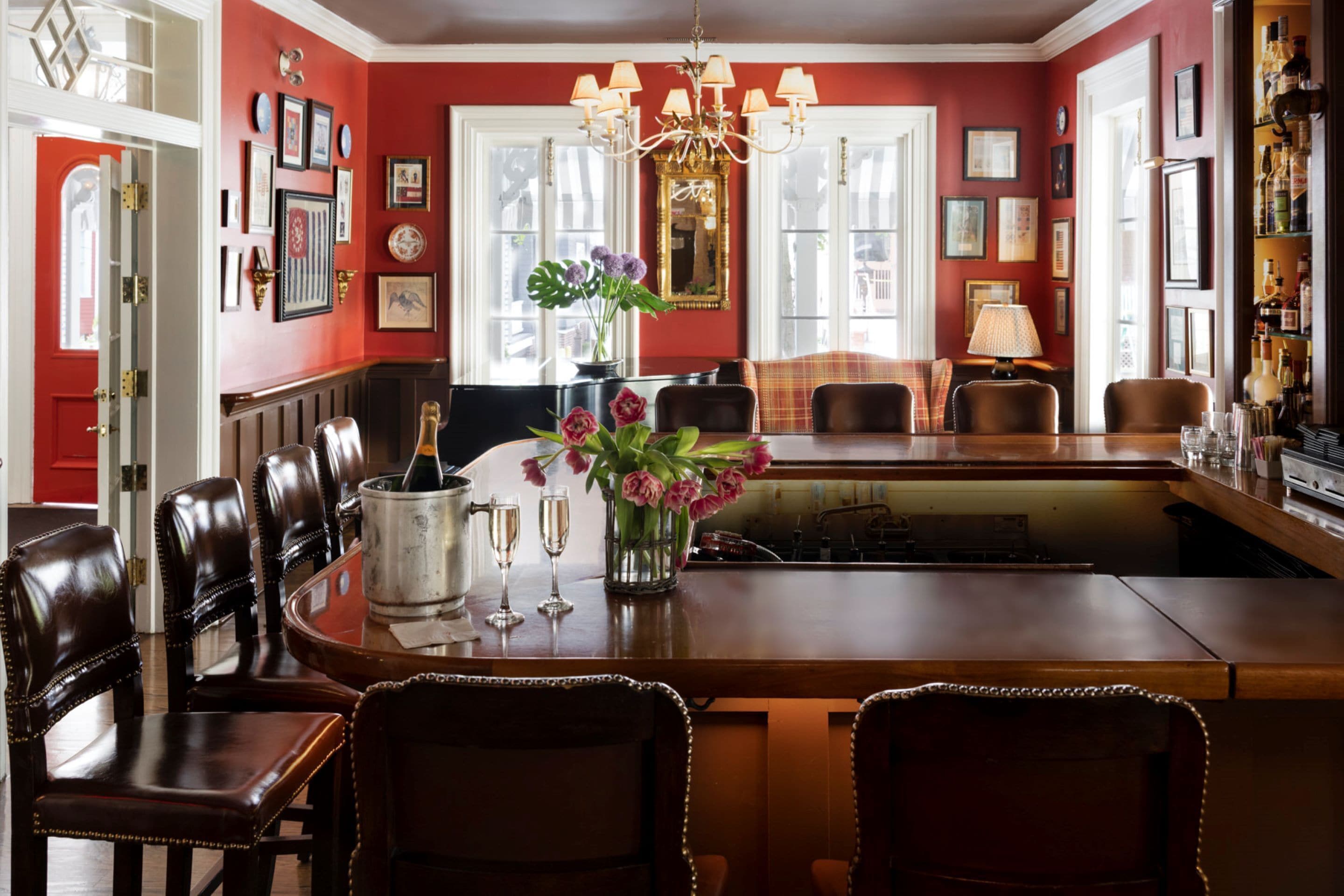 A dining area with a wooden table, leather chairs, a chandelier, and a vase of flowers.