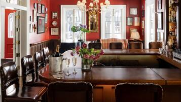 A dining area with a wooden table, leather chairs, a chandelier, and a vase of flowers.