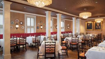 Un restaurante con varias mesas y cabinas, sillas de madera y una pared de ladrillo decorada con platos.