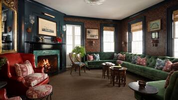 Un salón tradicional con chimenea, sofá verde, sillón rojo y una mesa de comedor.
