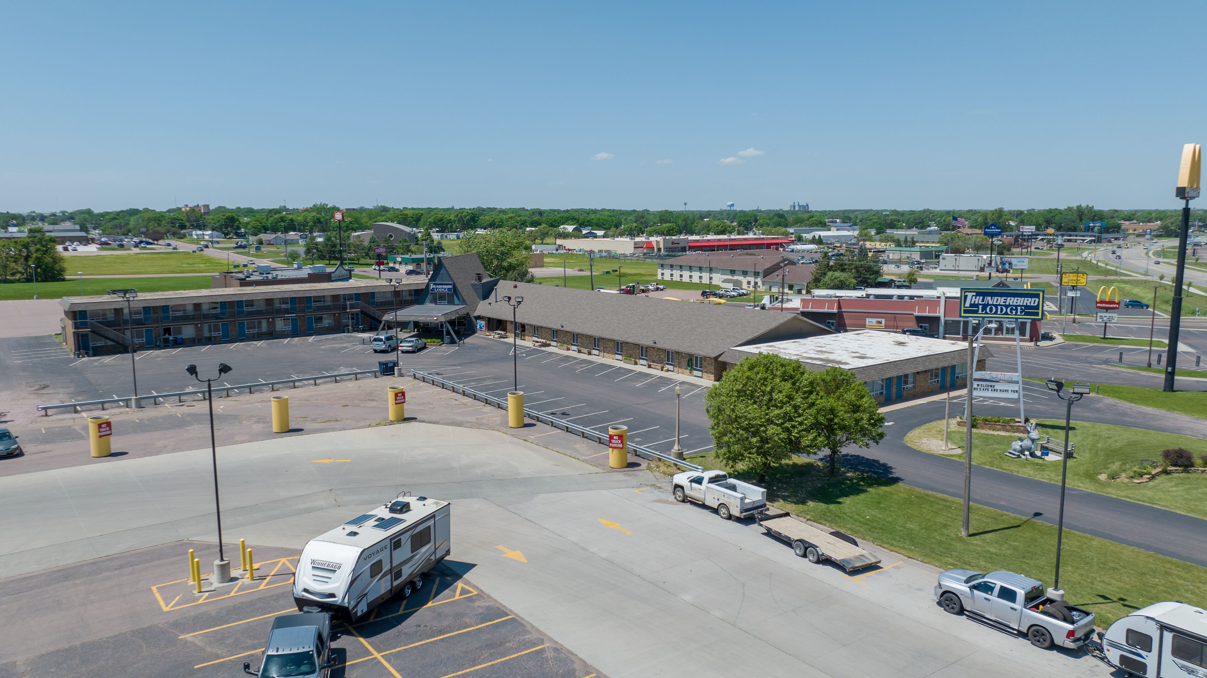 A parking lot with RVs and a building with a sign for 'Thunderbird Lodge'.