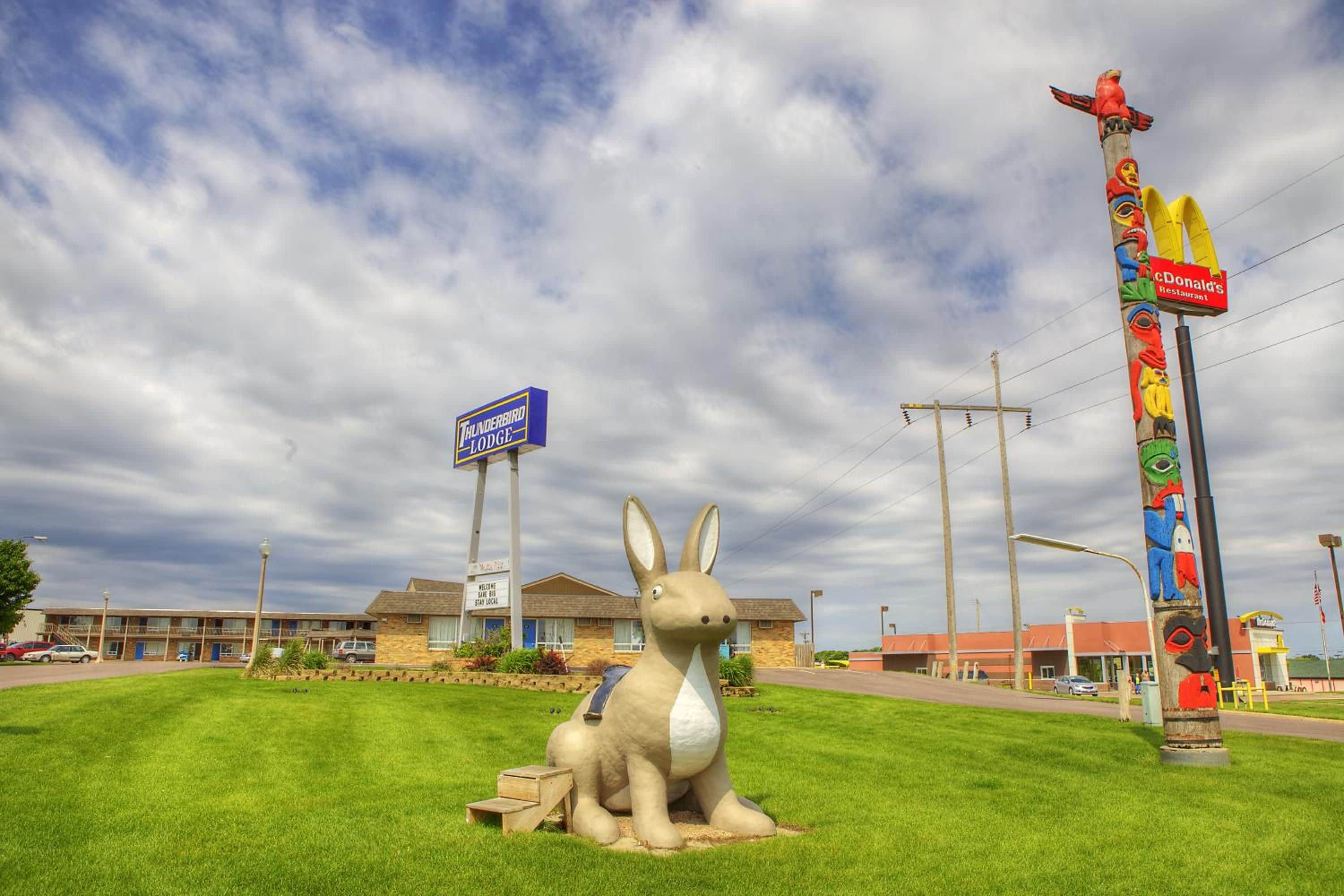A motel with a large outdoor statue of a rabbit, a Thunderbird Lodge sign, and a McDonald's sign.