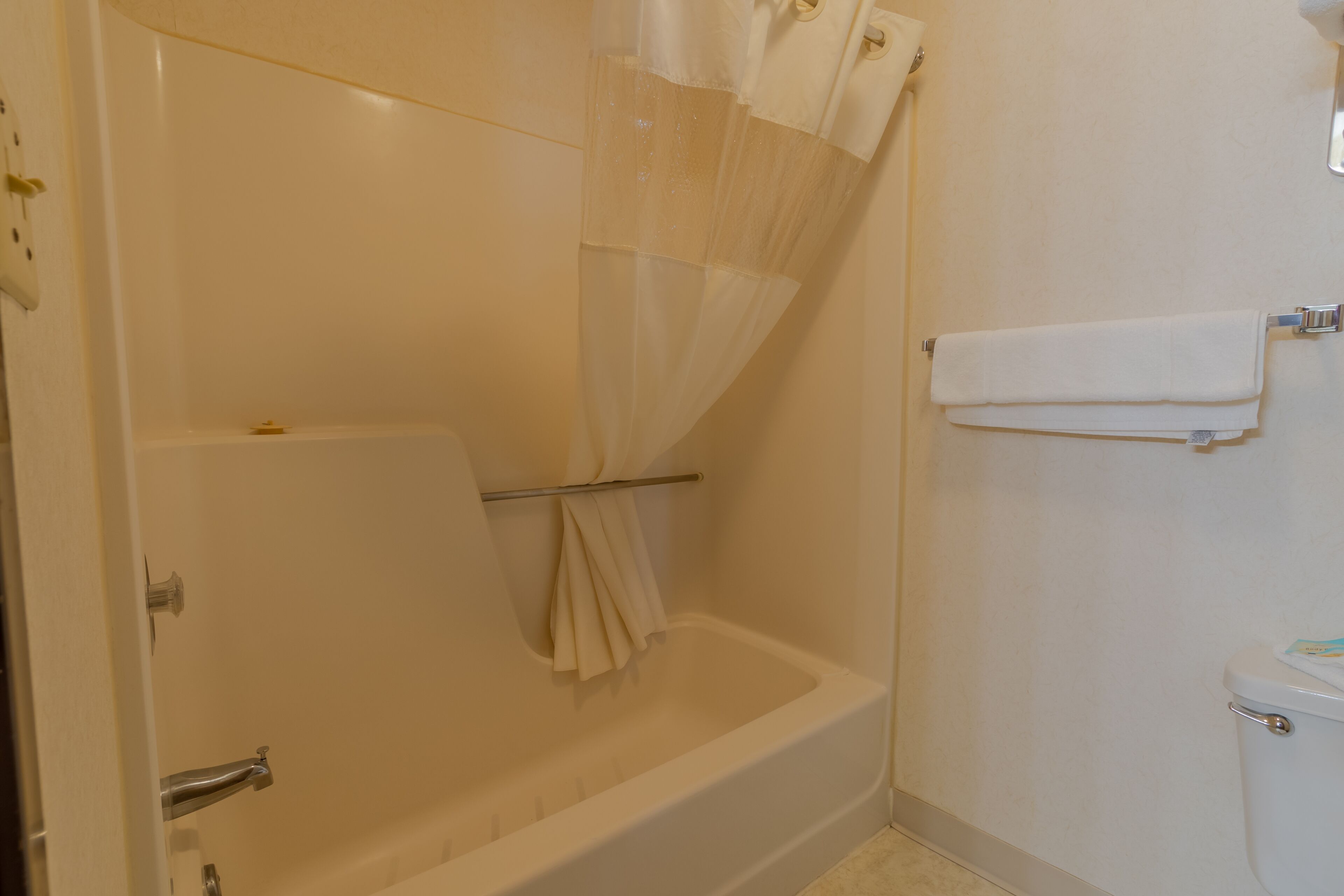 A bathroom with a bathtub, a toilet, and a shower curtain.
