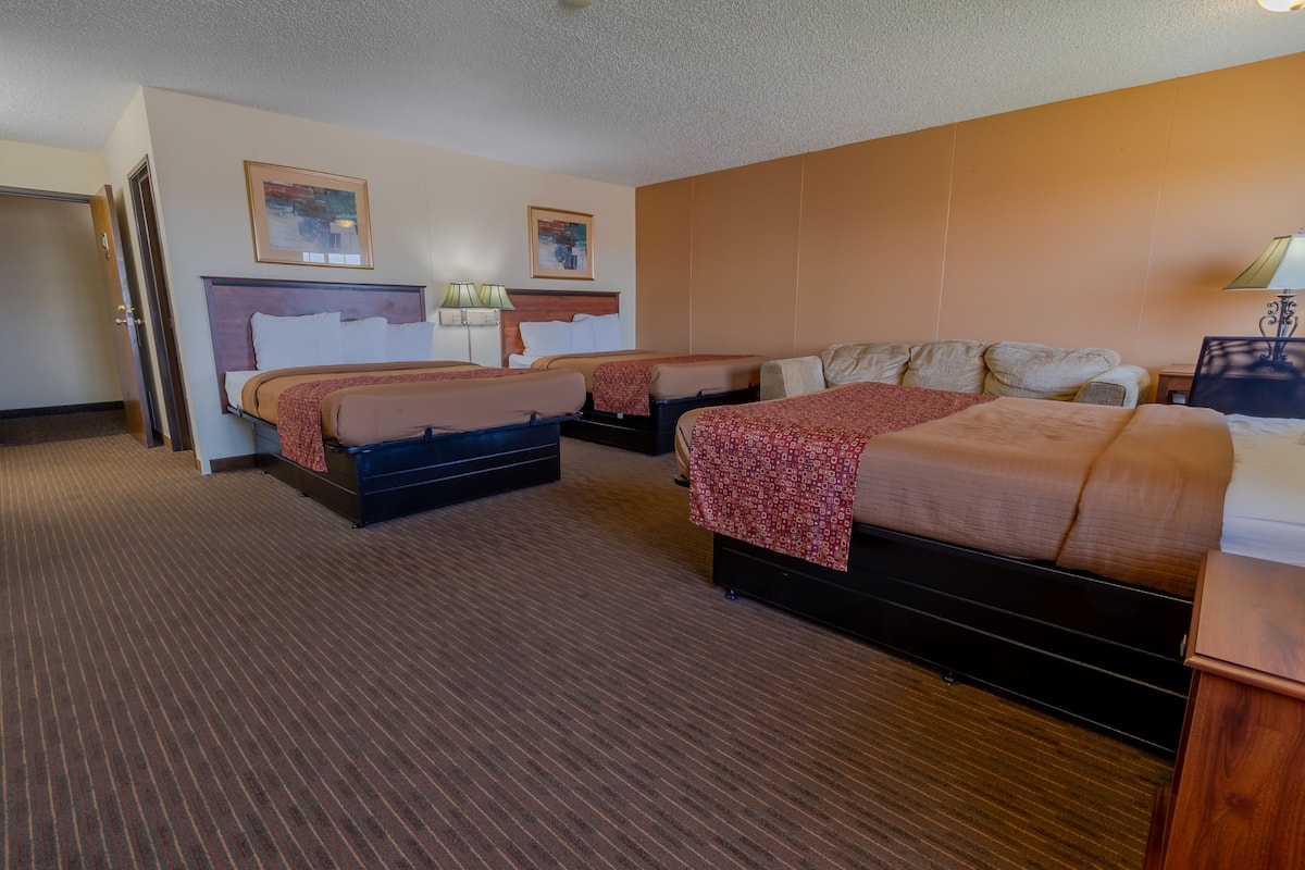 Ein Hotelzimmer mit zwei Betten, einem Holzkopfteil, Teppichboden und einem Bild an der Wand.