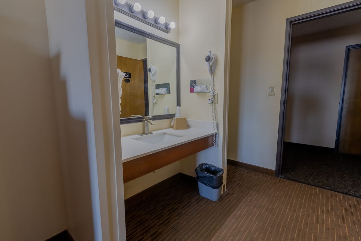 Ein Hotelbadezimmer mit Waschbecken, Spiegel und Fön.