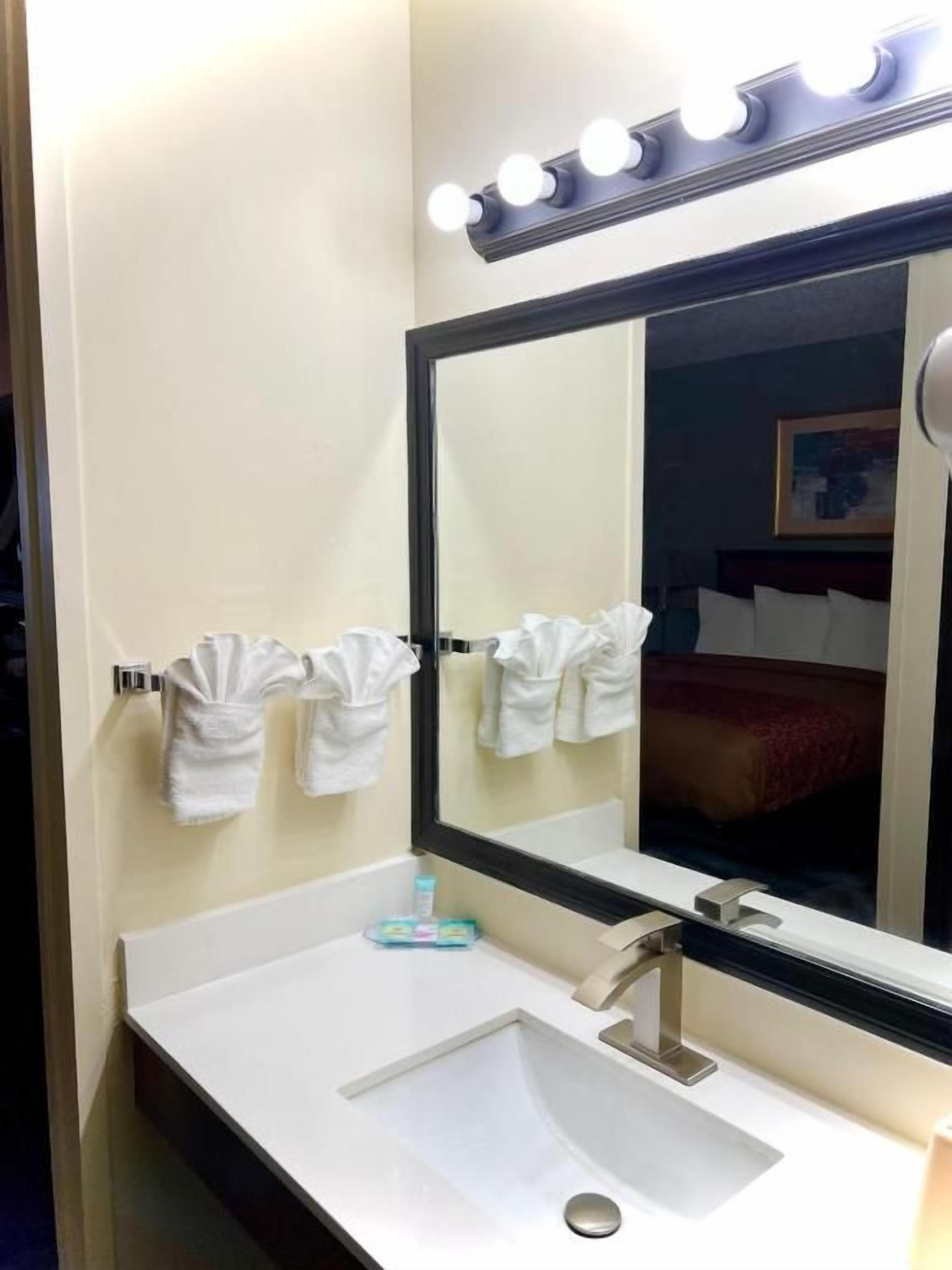 Un baño con lavamanos, espejo y perchero para toallas.