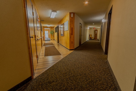 A hotel hallway with wooden paneling, a patterned carpet, and a clock on the wall.