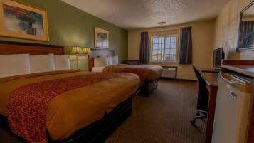A hotel room with two beds, a desk, a television, and a window with curtains.