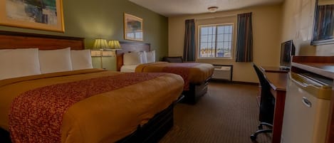 A hotel room with two beds, a desk, a television, and a window with curtains.