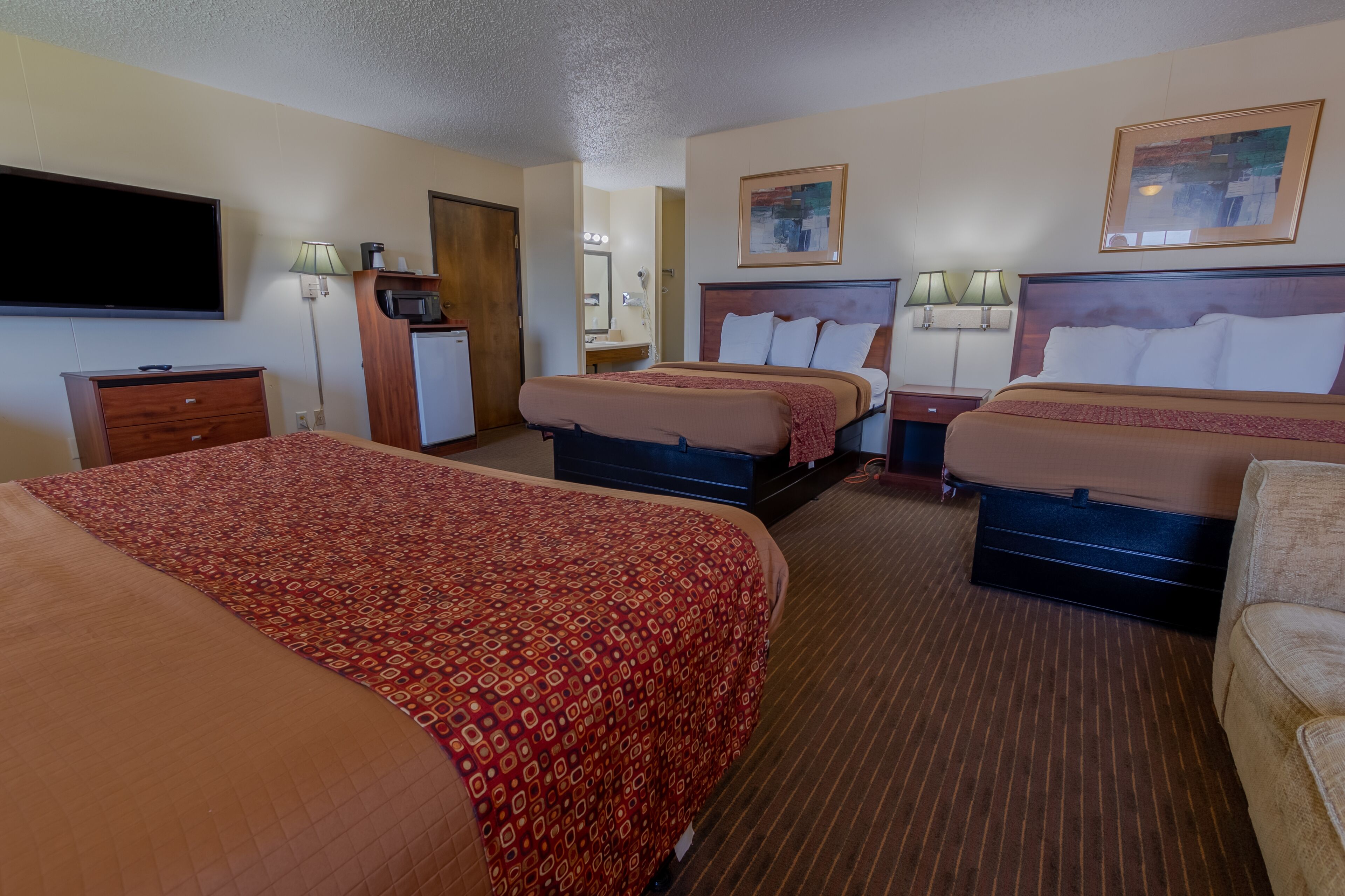 A hotel room with two beds, a TV, a desk, and a mirror.