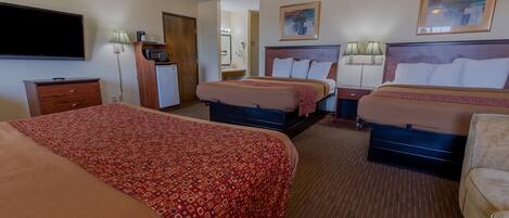 A hotel room with two beds, a TV, a desk, and a mirror.