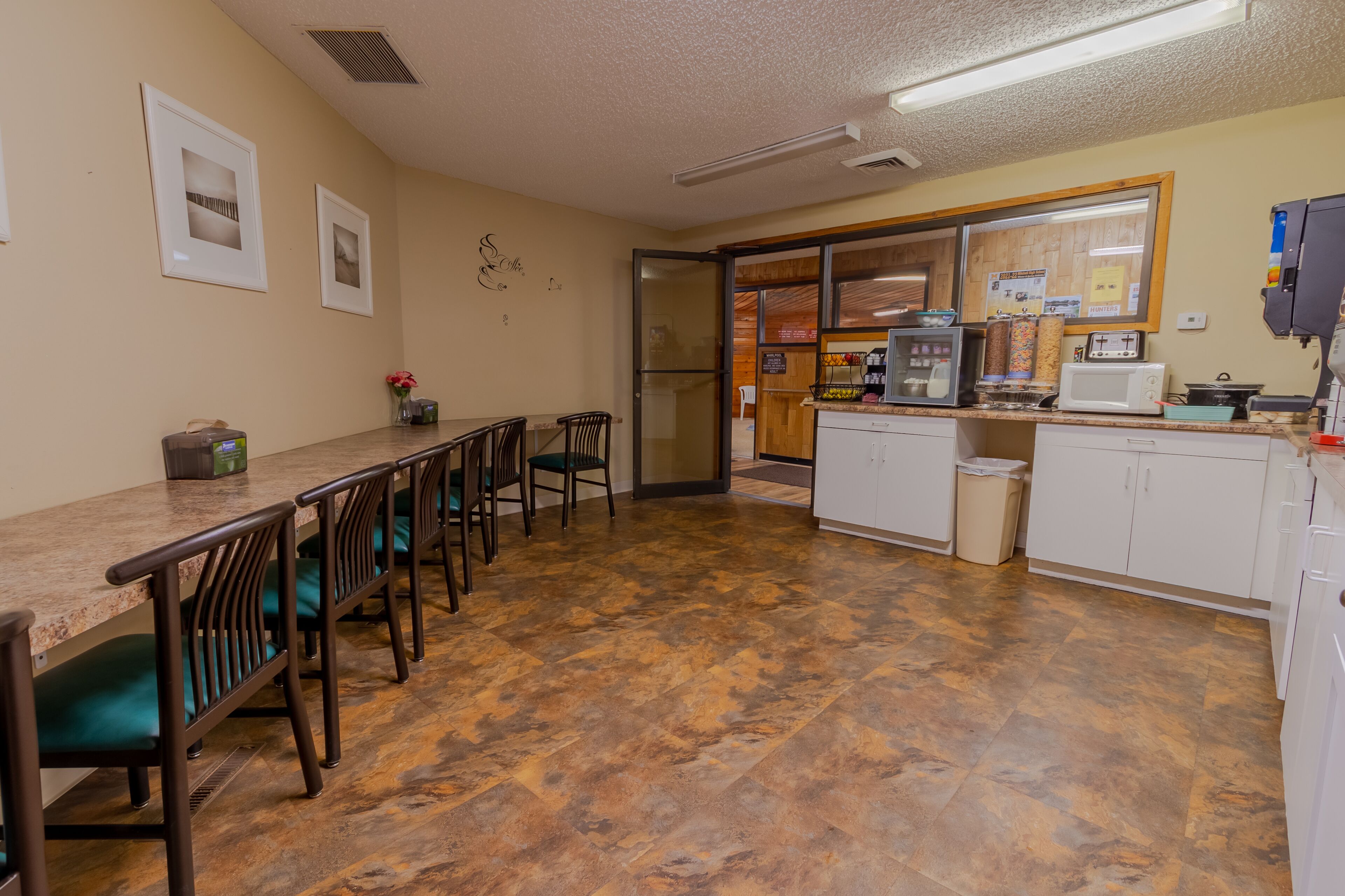 A kitchen with a counter, chairs, and a refrigerator.