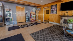 A lobby with a reception desk, a clock, a refrigerator with beverages, a snack bar, and a fireplace. - Thunderbird Lodge (Mitchell)