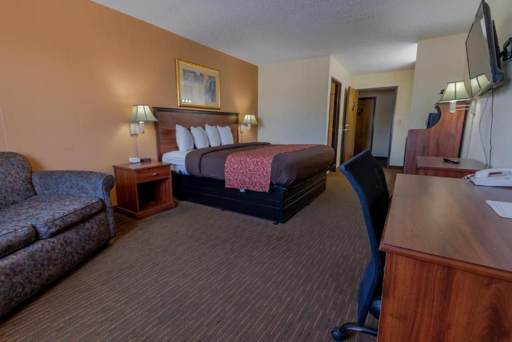 Una habitación de hotel con cama, escritorio, silla, sofá y televisor.