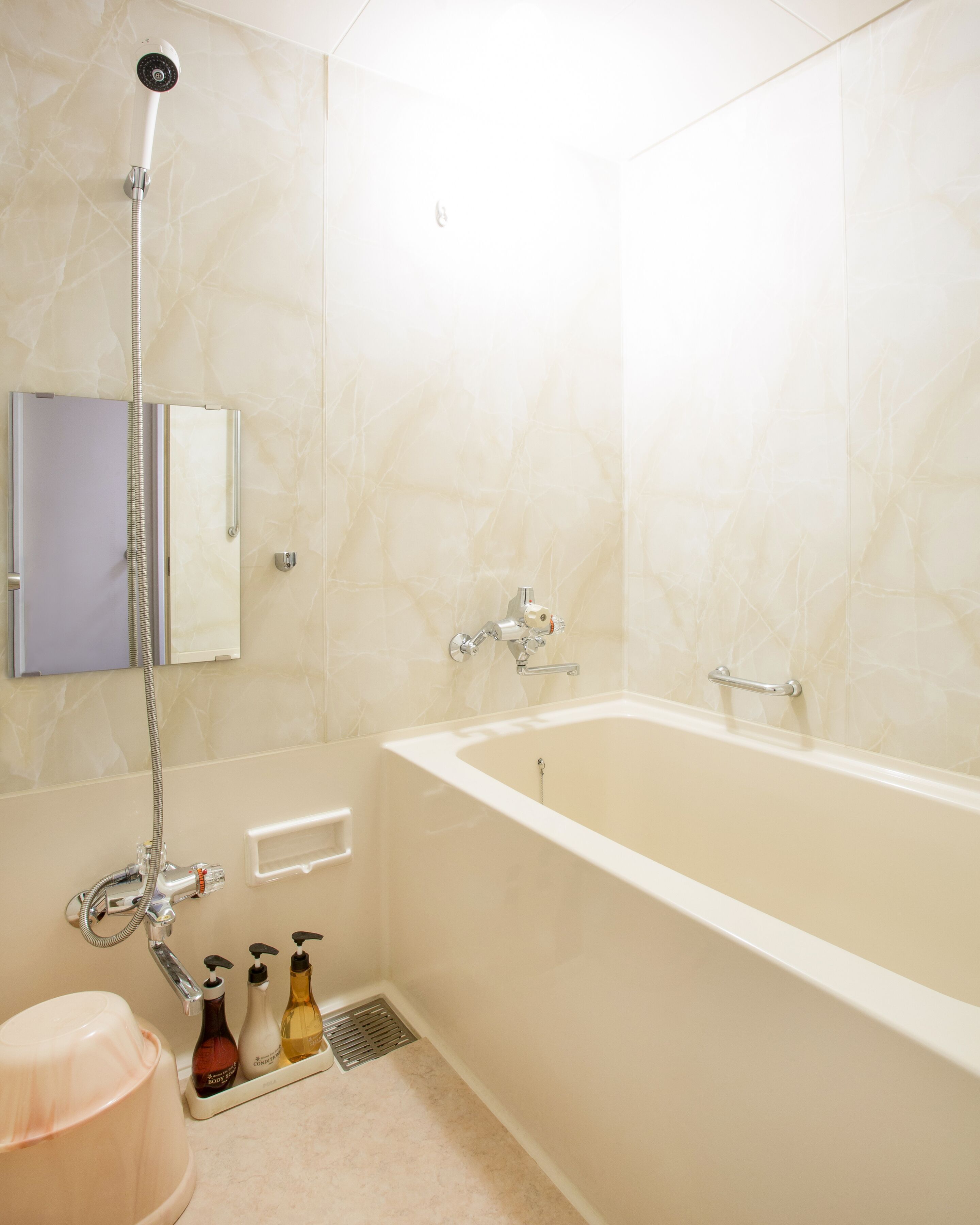 Een badkamer met een bad, douche en toilet. Er liggen toiletartikelen op de vloer.