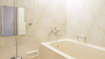 Een badkamer met een bad, douche en toilet. Er liggen toiletartikelen op de vloer.